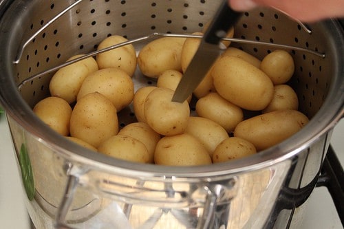 Checking doneness of steamed potato with a knife.