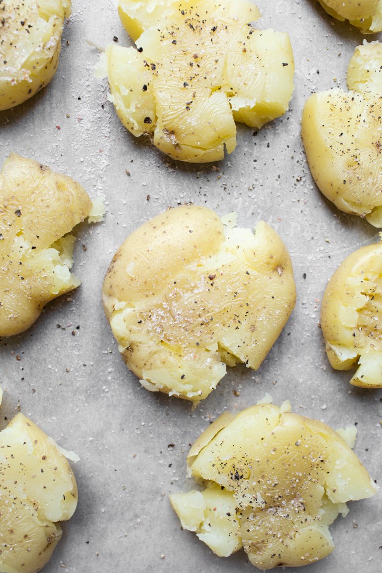 gold potatoes on pan smashed with spatula
