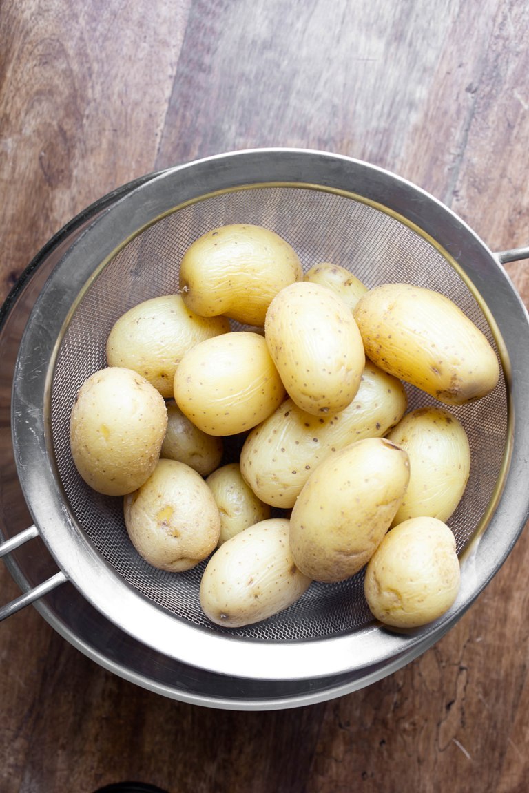 gold potatoes being strained into a bowl
