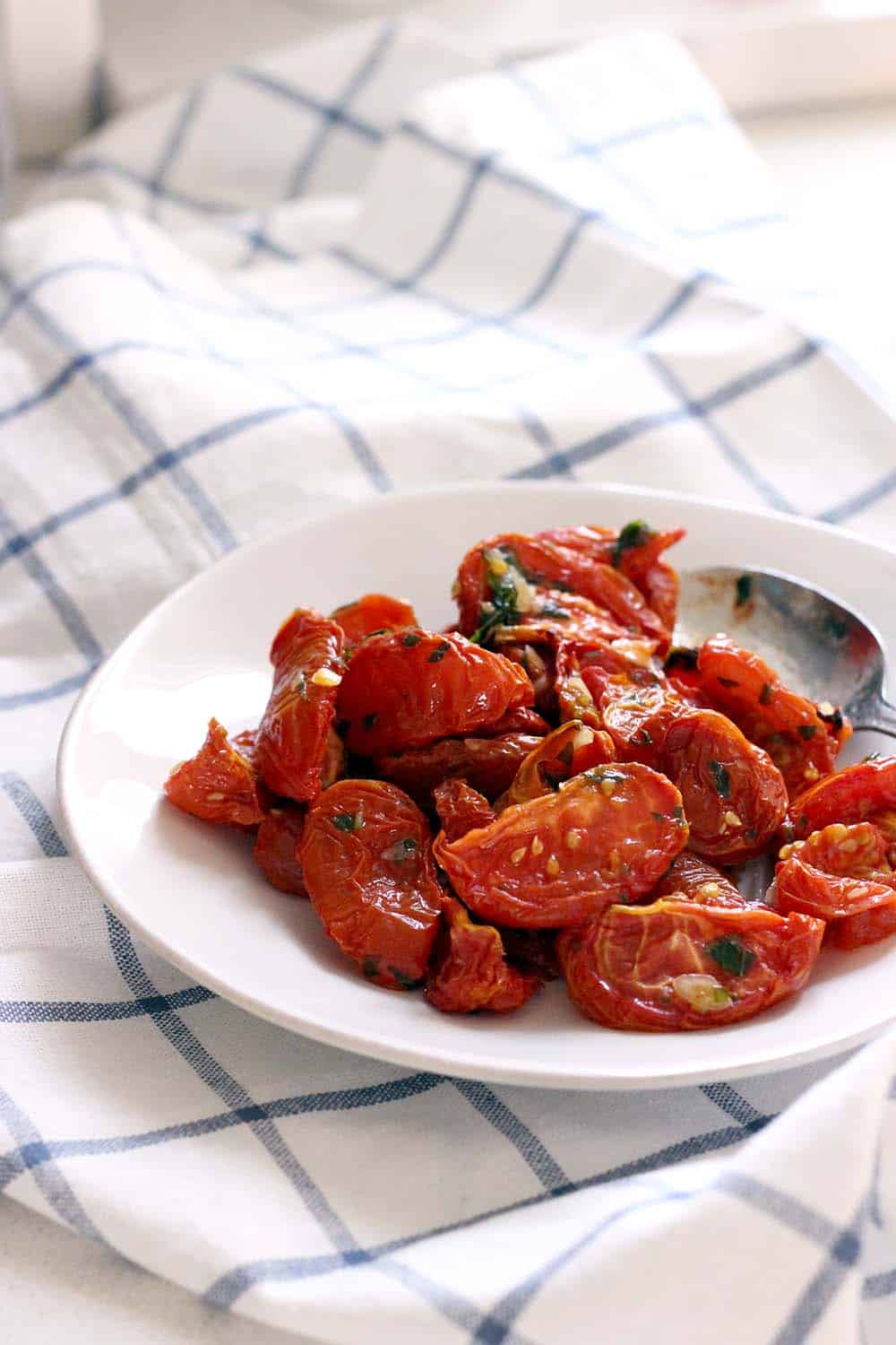 These Oven Dried Tomatoes, like sun dried, have a deep, smoky flavor and are covered in a delicious garlic and herb infused olive oil. Put them in salads, on pizza, or in sandwiches. Paleo, whole30, and healthy!
