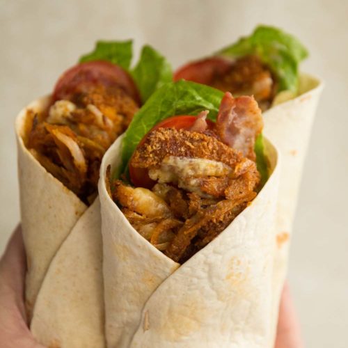 holding up crispy chicken wraps, focus on front one