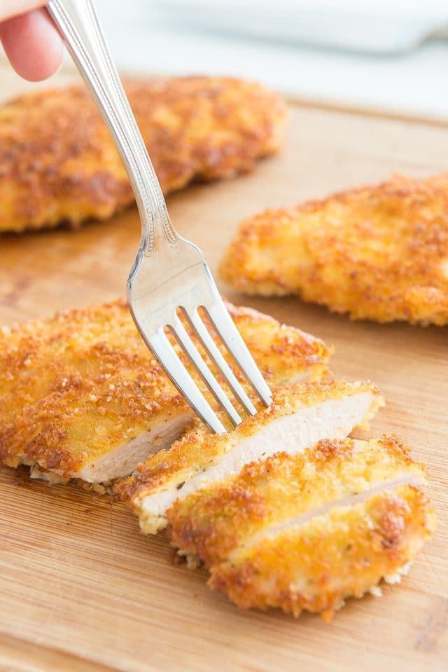 Parmesan Crusted Chicken - Sliced On a Wooden Board with Fork Digging In